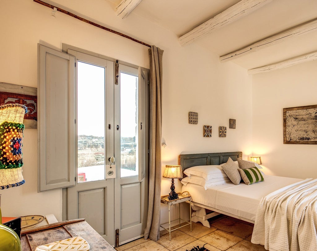 Stone-walled rustic Italian bedroom with traditional whitewashed decor, antique wooden furniture, and soft natural light through arched windows