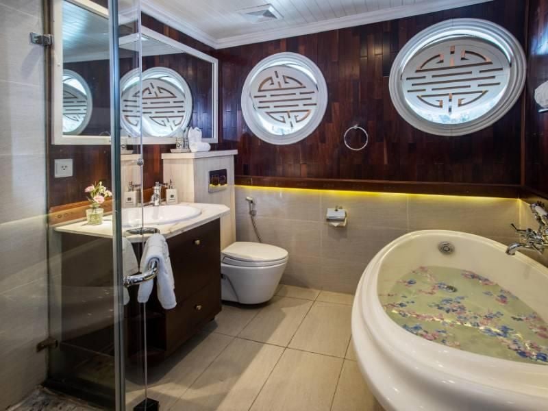 Luxurious Au Co Suite aboard Bhaya Cruises, featuring elegant Vietnamese-inspired decor, expansive windows overlooking emerald Halong Bay waters, plush king-sized bed