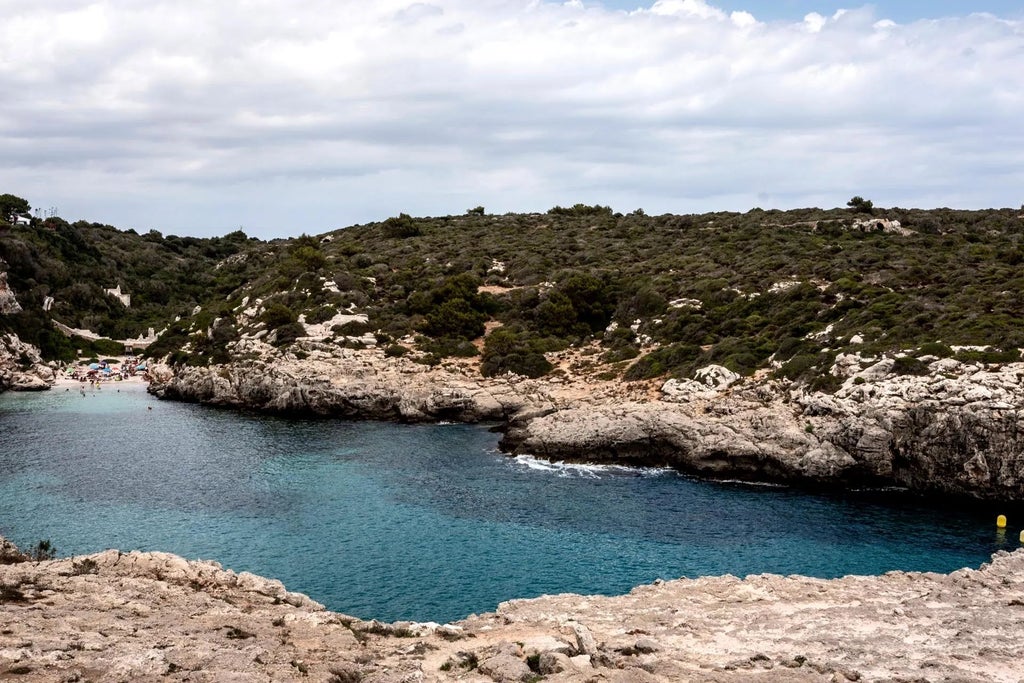 Luxurious whitewashed Spanish villa with rustic stone walls, surrounded by lush Mediterranean greenery and soft natural light in Menorca.