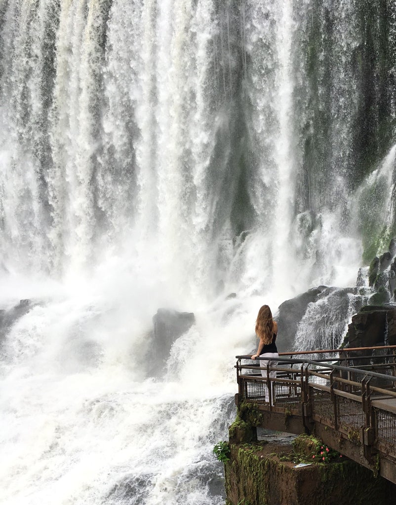 Majestic Iguazu Falls cascading over moss-covered cliffs with lush rainforest backdrop, illuminated by golden sunlight and misty spray