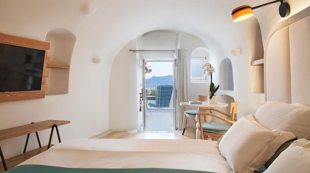 White-washed luxury suites with private infinity pools cascade down Santorini's caldera cliffs, overlooking the azure Aegean Sea at sunset