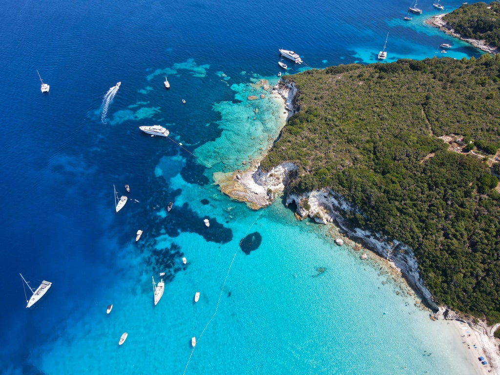 Luxury yacht cruising turquoise Ionian waters, passing lush green Paxos and Antipaxos islands under bright Mediterranean sunlight, revealing pristine coastal scenery.