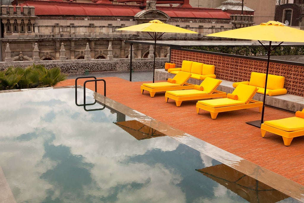 Elegant rooftop terrace of Downtown Mexico hotel with colonial architecture, vibrant Mexican textiles, and panoramic city skyline at sunset