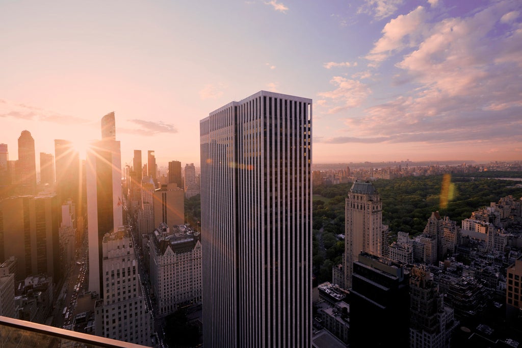 Towering Art Deco-style luxury hotel in Manhattan with limestone facade, gold-trimmed entrance, and elegant doorman under evening lights