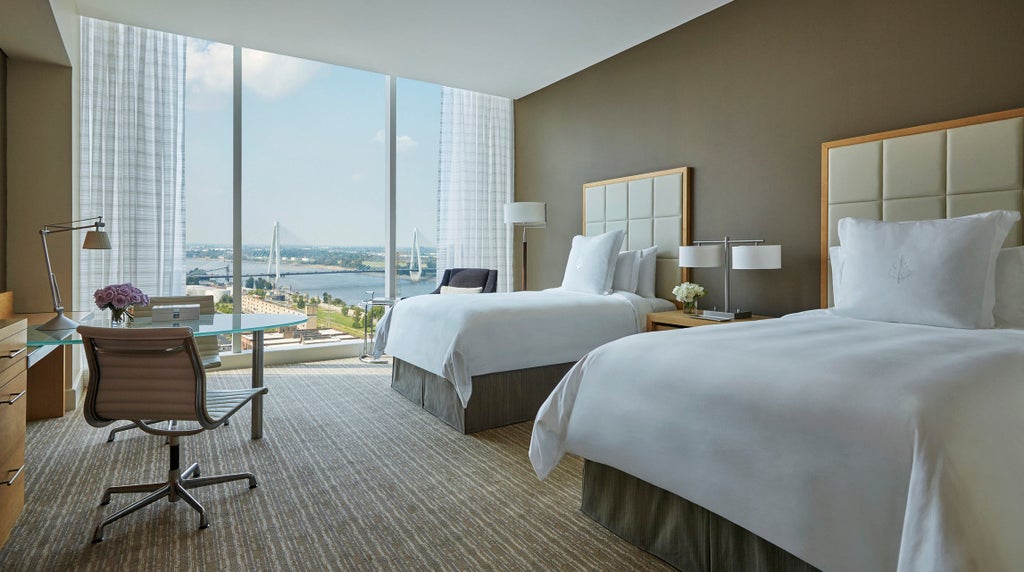 Elegant high-rise Four Seasons hotel in downtown St. Louis with curved glass facade reflecting cityscape and Mississippi River at sunset