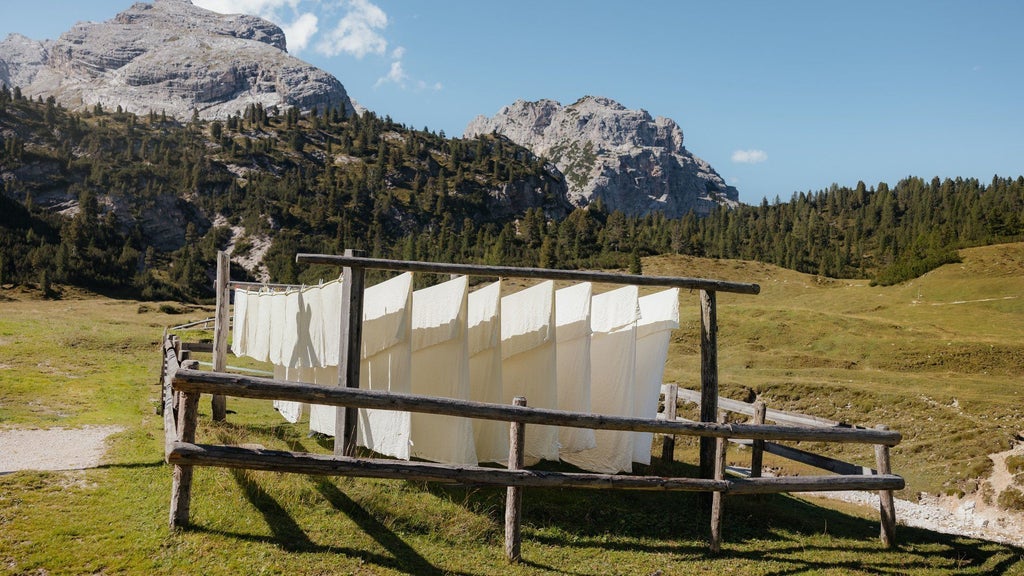 Rustic mountain lodge Fodara Vedla nestled in green Alpine meadows, surrounded by dramatic Dolomite peaks and forest trails