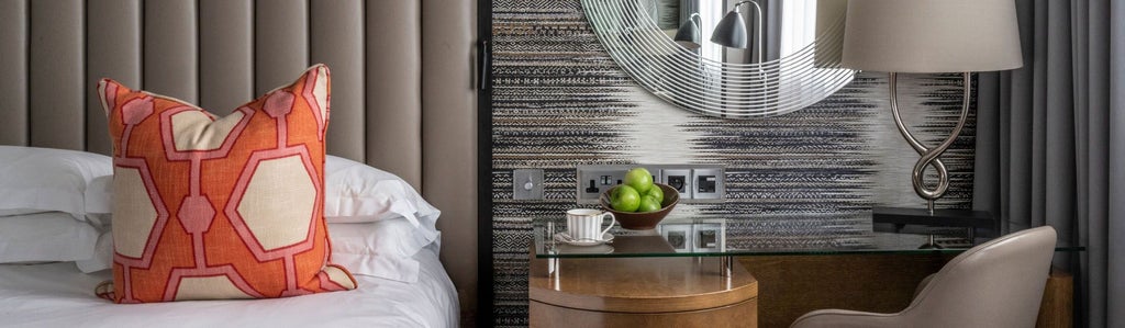 Elegant deluxe hotel room at stylish boutique property with plush queen bed, contemporary furnishings, and soft neutral color palette in central London setting