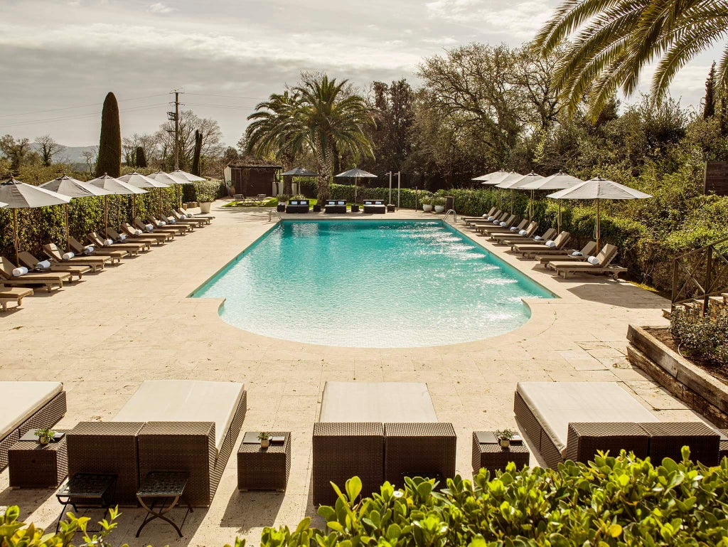 Elegant Mediterranean villa with terracotta roof and manicured gardens, featuring a pristine pool surrounded by stone terraces and cypress trees