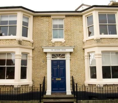 Elegant boutique hotel room with maritime-inspired decor, crisp white linens, wooden furniture, and soft coastal lighting in Southwold, United Kingdom