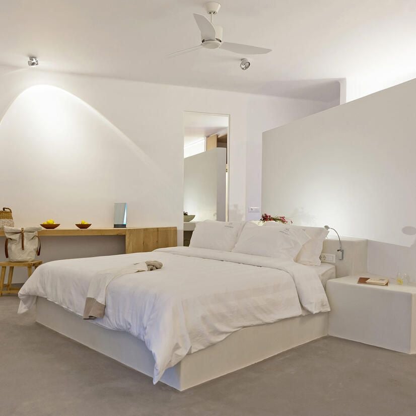 Luxurious white-walled Aegean suite with panoramic scenset views, plush king bed, and elegant minimalist design highlighting traditional Greek island architecture