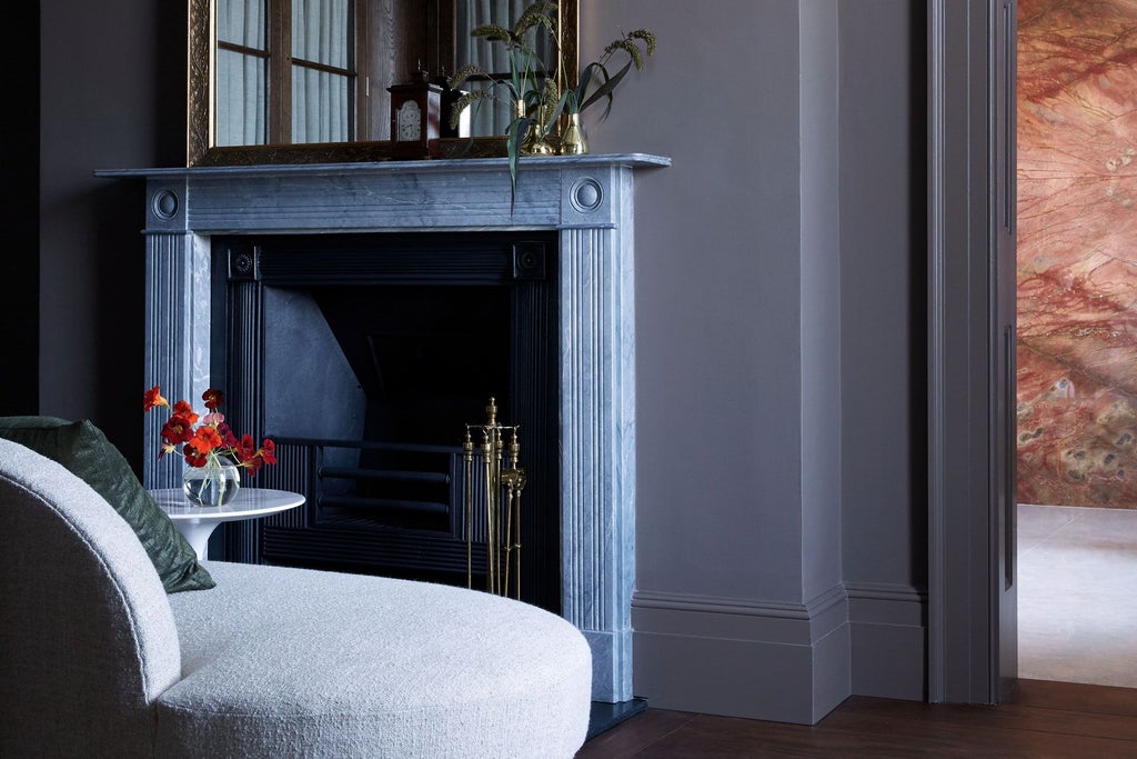 Elegant earth-toned contemporary hotel room with natural wood furnishings, soft linens, and expansive window overlooking lush British countryside landscape