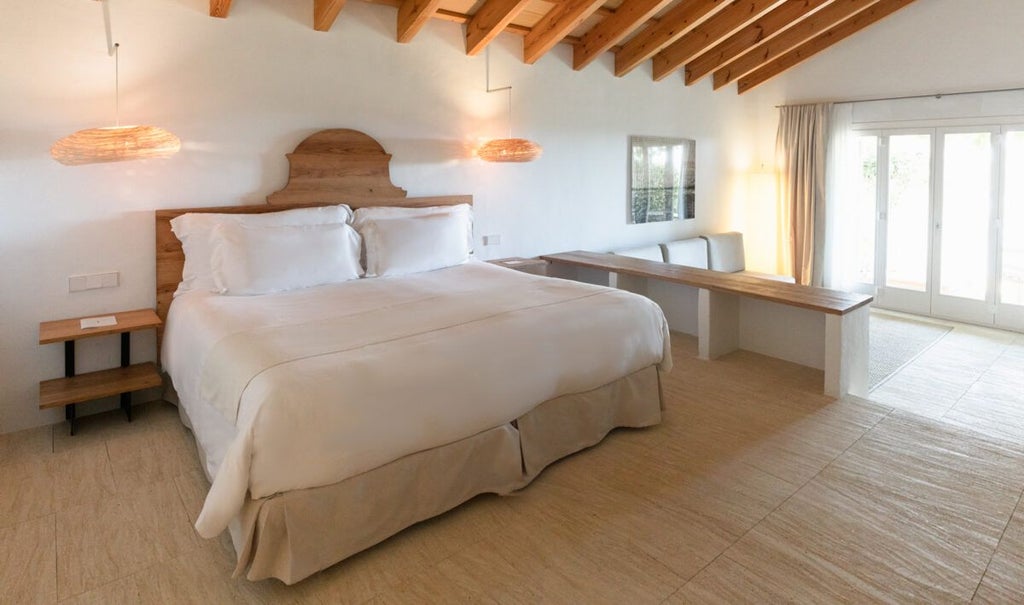 Elegant whitewashed Spanish coastal room with minimalist design, panoramic sea view, crisp linens, and rustic stone wall at luxurious Scenset retreat