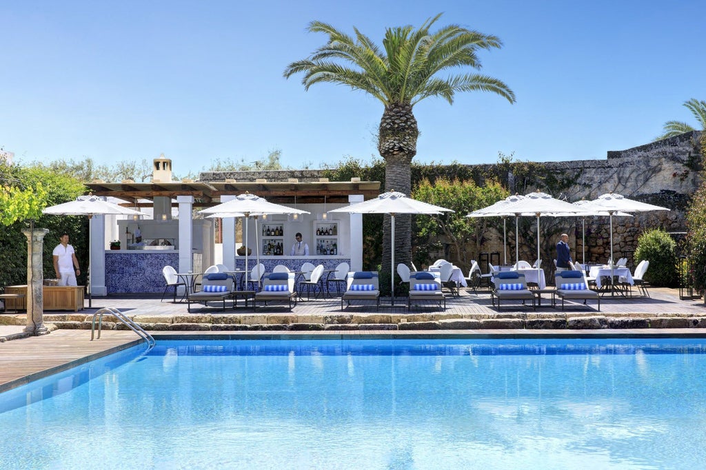 Elegant Mediterranean hotel courtyard with whitewashed walls, stone archways, potted olive trees and antique lanterns at sunset