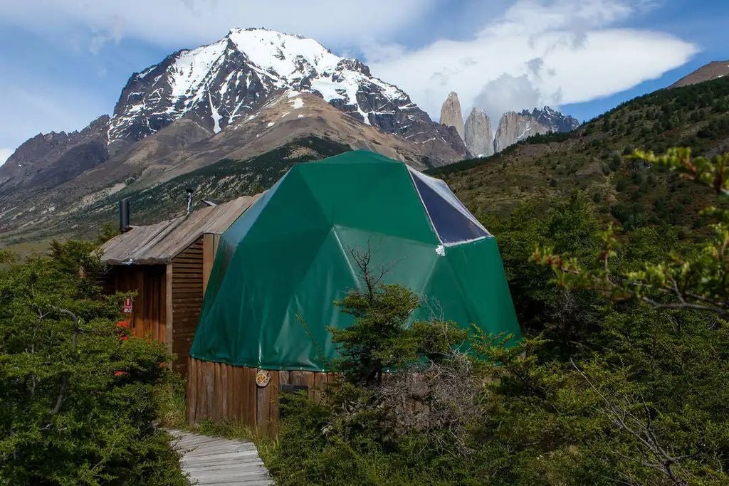 Geodesic dome suites nestled in Torres del Paine mountains, with snow-capped peaks and pristine wilderness as dramatic backdrop