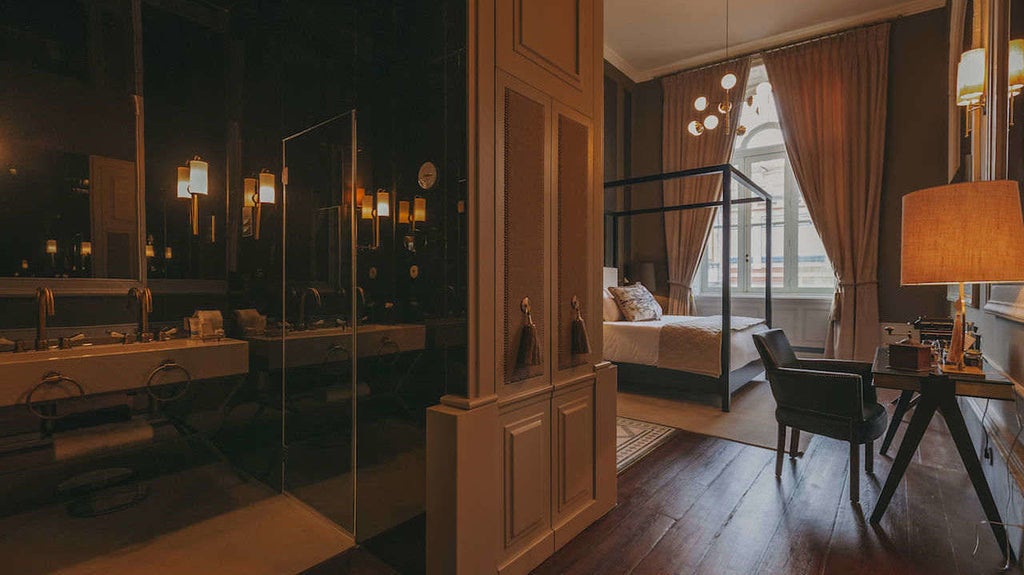 Elegant 19th century boutique hotel facade with ornate stone architecture, wrought iron balconies and towering arched windows in Porto