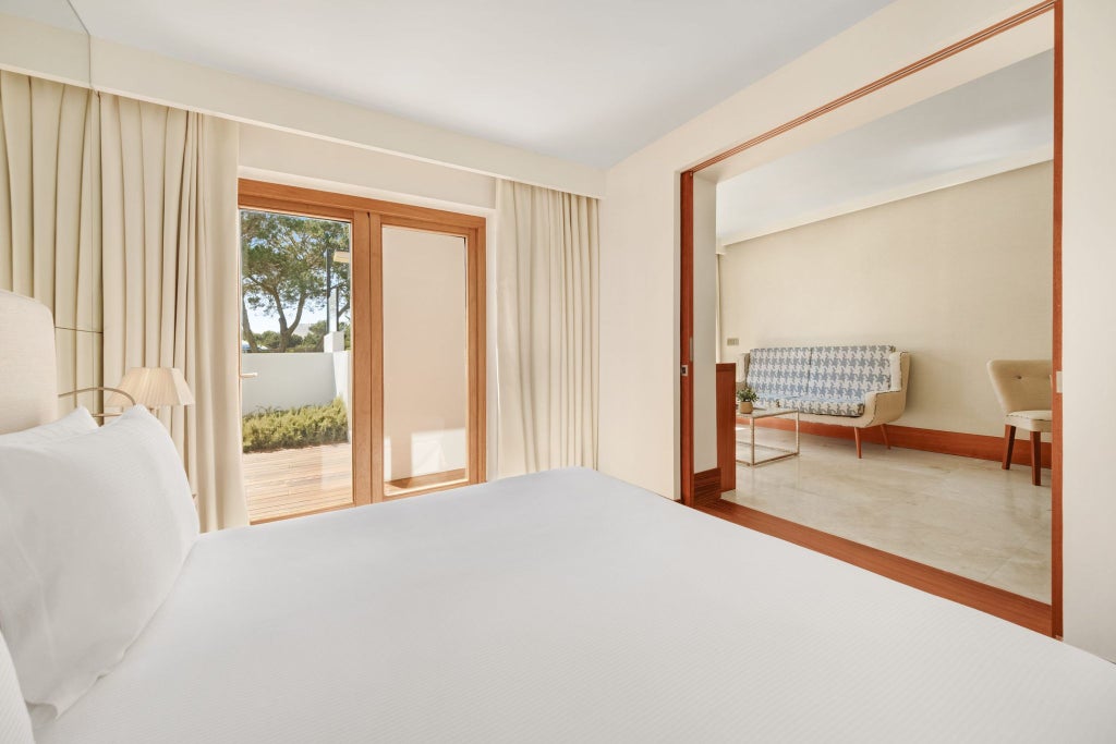 Luxurious Gran Pool Garden room at Gecko Hotel, featuring modern design, plush white bedding, and expansive glass doors overlooking lush tropical vegetation in Spain.