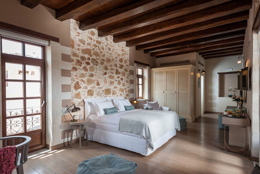 Elegant marble-floored superior suite with private terrace overlooking Grecian coastline, featuring plush king bed and contemporary Mediterranean design elements