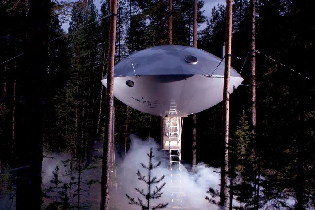 Futuristic UFO-shaped hotel room suspended among pine trees in Swedish forest, featuring sleek metallic design with large panoramic windows and minimalist interior