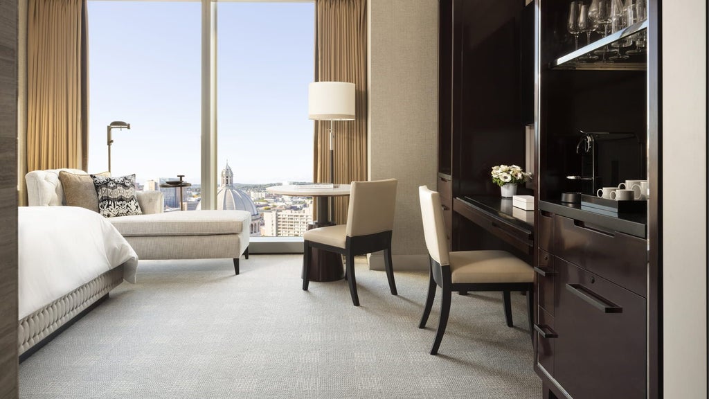 Luxurious deluxe hotel room at Four Seasons in Boston with expansive city skyline view, floor-to-ceiling windows, and modern contemporary design