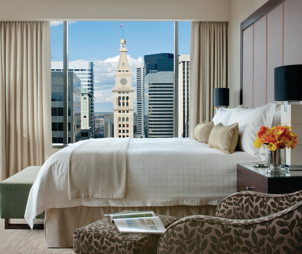 Luxurious Four Seasons Denver hotel exterior features modern glass tower with sleek architecture, illuminated entrance and manicured landscaping