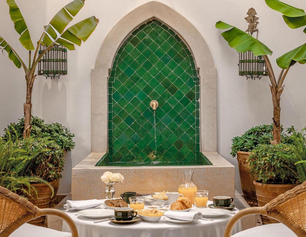 Elegant Moroccan riad with ornate white archways, turquoise pool surrounded by lush palms and traditional tilework in tranquil courtyard