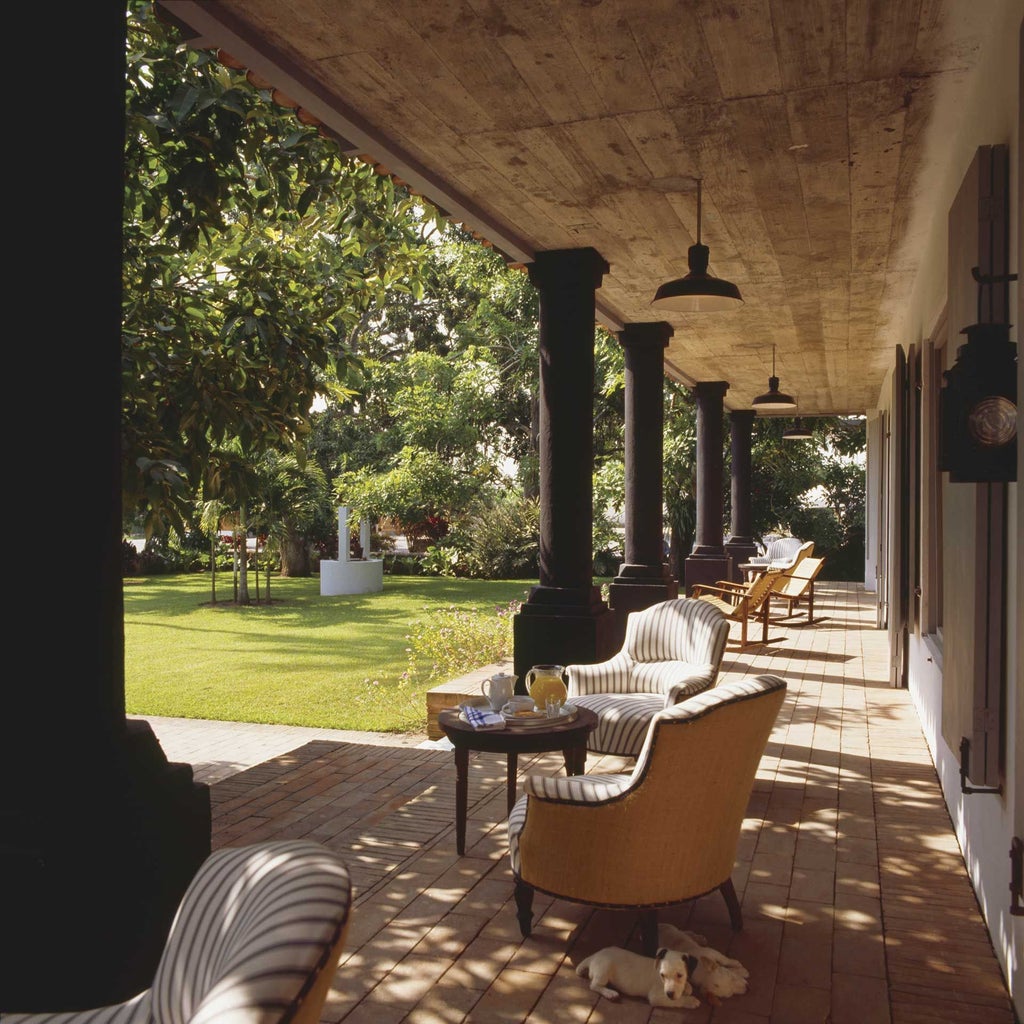 Luxurious Mexican colonial-style hotel with lush gardens, vibrant colors, and elegant archways set against a serene tropical landscape near coastal scenery