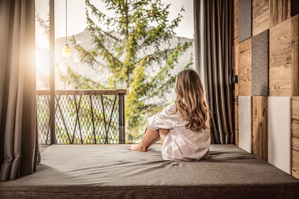 Luxurious treetop suite with floor-to-ceiling windows overlooking lush forest canopy, modern minimalist design with elegant wooden furnishings and soft ambient lighting