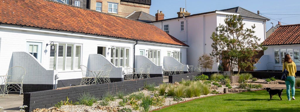 Luxurious coastal hotel room at The Swan in Southwold, featuring elegant white decor, crisp linens, and panoramic window with seaside view