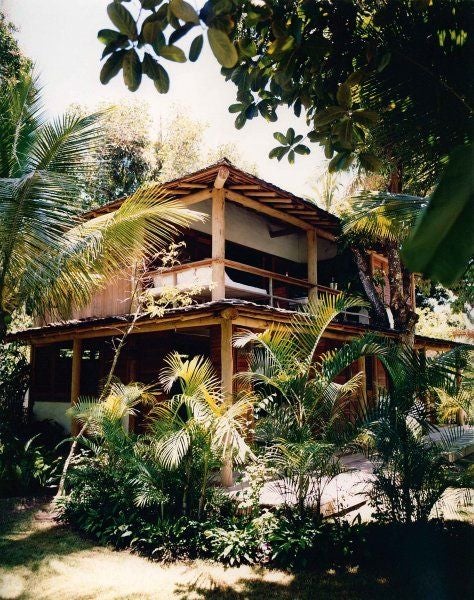 Rustic-chic Brazilian hotel room with wooden floors, white bedding, tropical greenery, and minimalist design at UXUA Casa Hotel and Spa in Trancoso