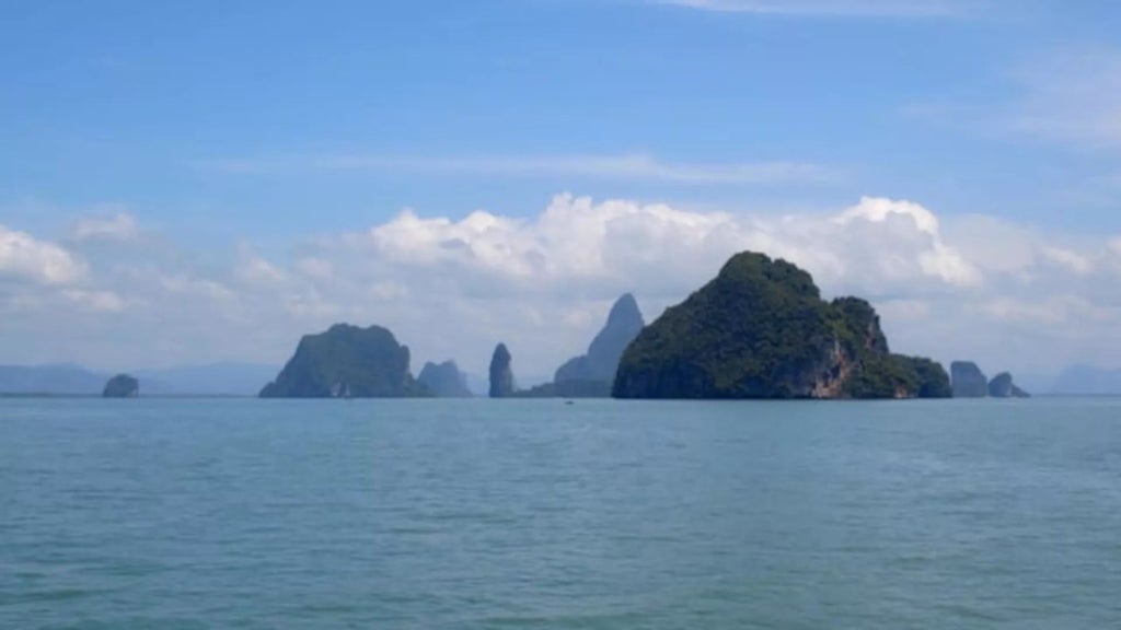 Luxurious COMO Point Yamu resort overlooking Phang Nga Bay, with sleek modern architecture, infinity pool, and dramatic limestone cliffs in background