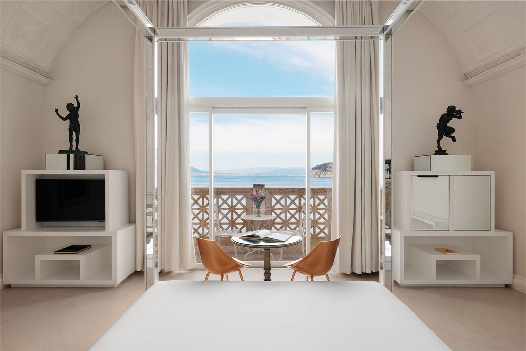 Elegant suite with panoramic coastal view, plush king bed, marble bathroom, and classic Italian decor overlooking scenic Sorrento coastline at Bellevue Syrene hotel