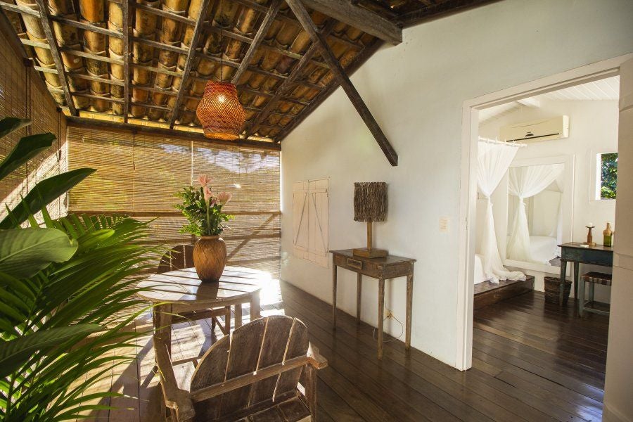 Luxurious boutique hotel room at UXUA Casa Hotel and Spa, featuring rustic wooden furniture, tropical textures, and elegant Brazilian coastal design elements.