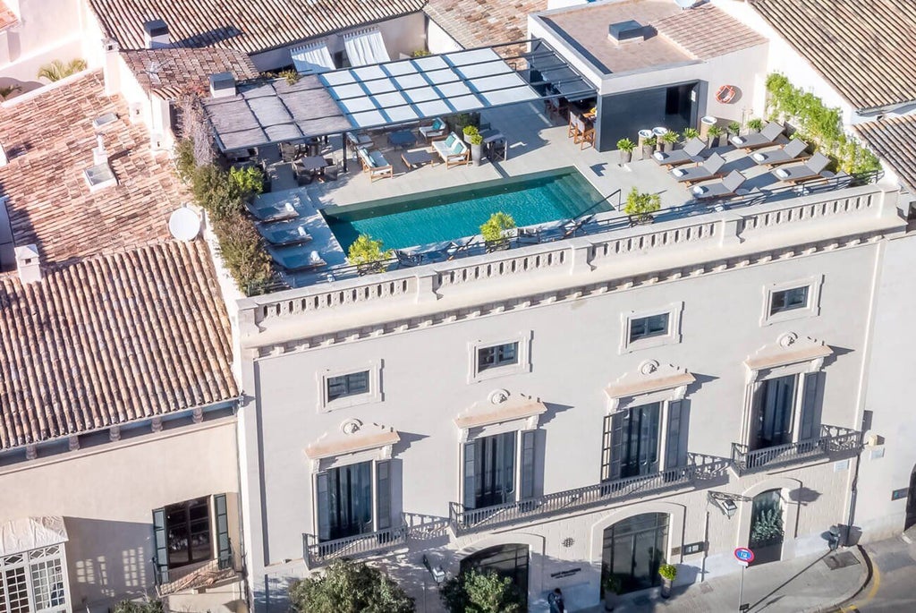 Luxurious stone facade of Sant Francesc Hotel Singular, with elegant balconies and warm golden light highlighting historic Spanish architectural details