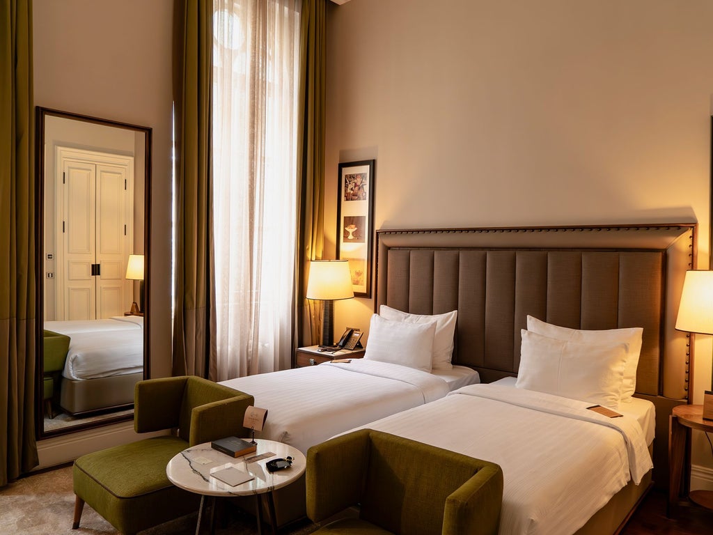 Elegant deluxe twin room with plush white beds, contemporary Turkish design, rich wooden furnishings, and soft ambient lighting in historic Istanbul hotel.