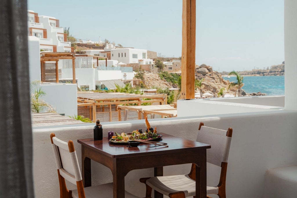 Elegant white-themed junior suite with panoramic sea view, minimalist design, modern furnishings, and private balcony overlooking Aegean blue waters at Branco Mykonos