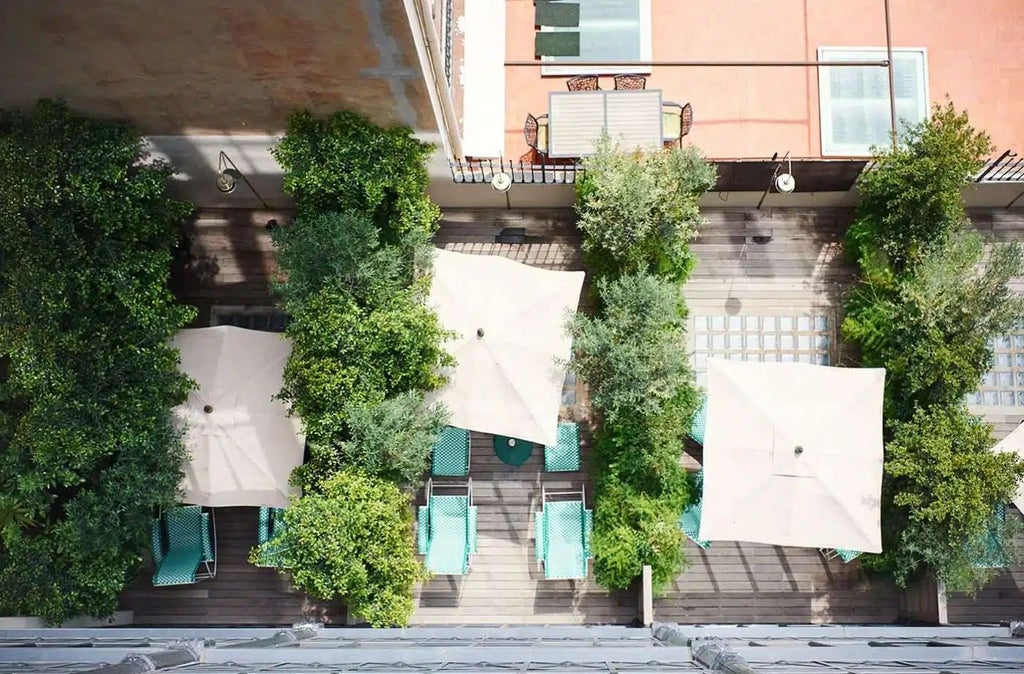 Sunlit Barcelona courtyard with lush greenery, vintage tile floors, and modern furniture at luxury boutique hotel Casa Bonay's expansive terrace