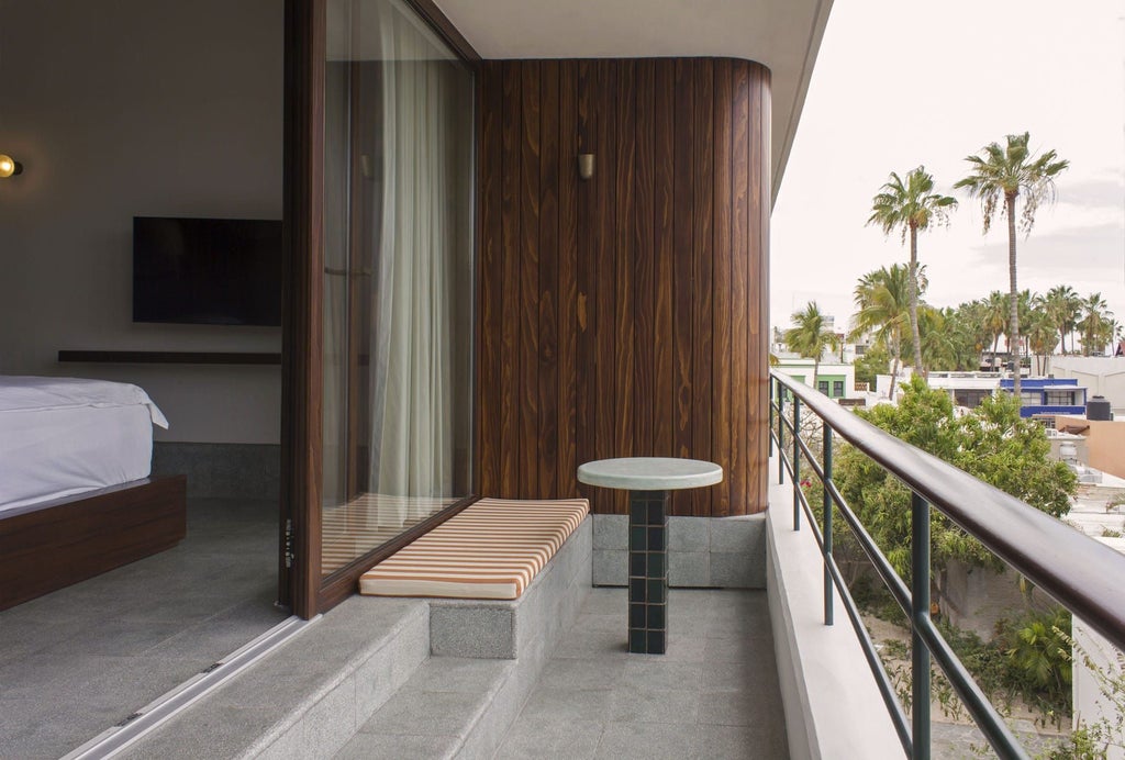 Luxurious beachfront hotel with minimalist white architecture, azure pool, and palm trees overlooking scenic Mexican coastline at sunset