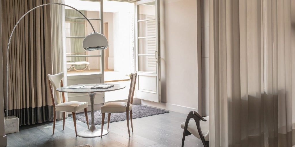 Elegant wooden-floored loft with minimalist design, large windows overlooking Tuscan landscape, featuring sleek furniture and warm natural lighting