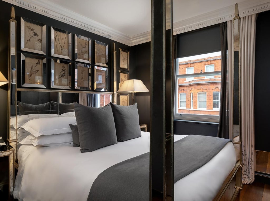 Elegant executive suite at a luxury UK hotel with plush king bed, modern metallic decor, floor-to-ceiling windows overlooking cityscape, and sophisticated neutral color palette