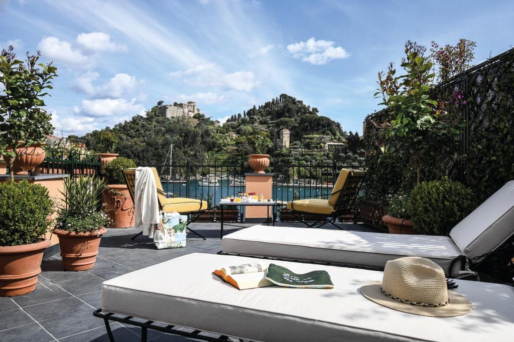 Elegant Mediterranean hotel overlooking turquoise sea, featuring white terraces, infinity pool, and manicured gardens against coastal cliffs