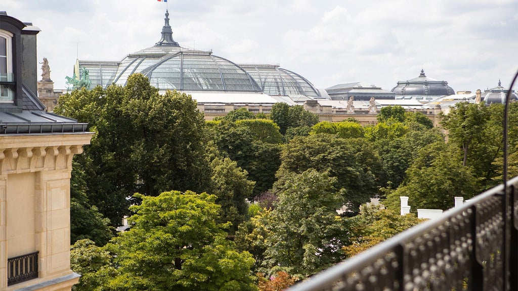 Elegant Parisian luxury hotel exterior with neoclassical architecture, manicured gardens, and soft evening lighting reflecting refined French hospitality