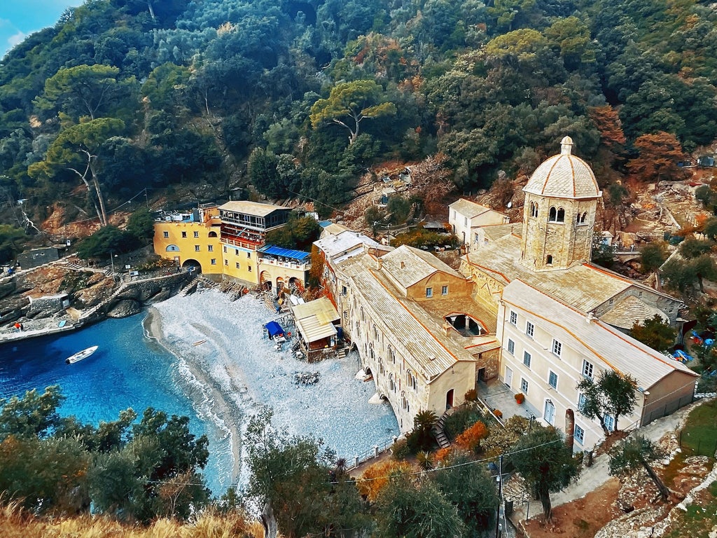 Coastal trail with ancient stone steps winding down steep cliffs to a secluded medieval abbey perched above turquoise Mediterranean waters