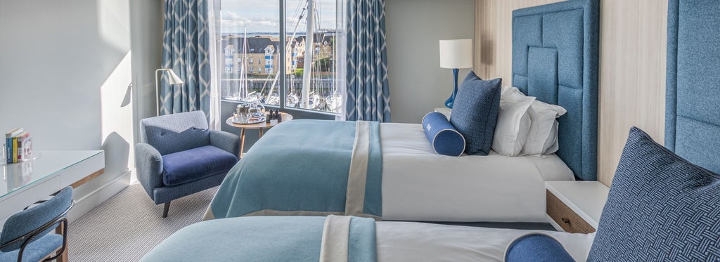 Twin hotel room with modern decor, crisp white linens, two comfortable beds, large window overlooking scenic harbour view in Southampton, UK.