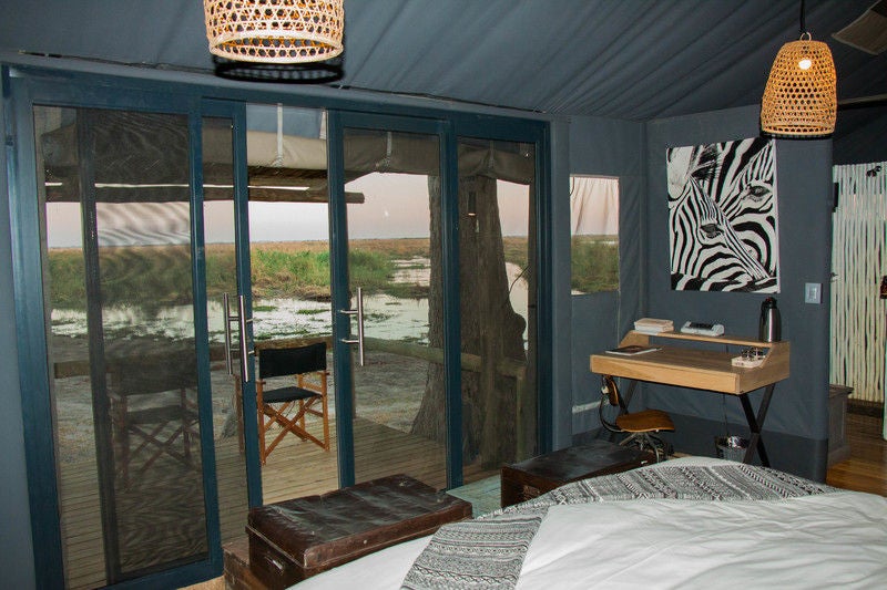 Elevated luxury tent suite overlooking Botswana savanna with plunge pool, wooden deck and canvas walls framing wilderness views