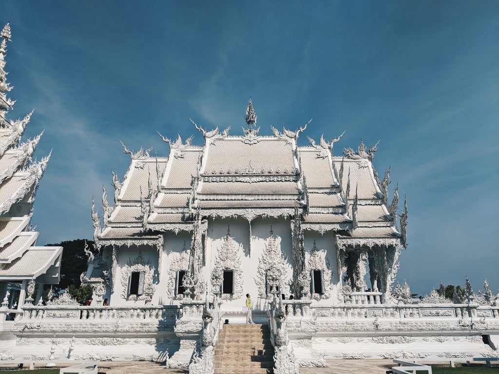 Golden reclining Buddha adorning ornate temple wall in Chiang Rai, with vibrant decorative details and traditional Thai architectural elements