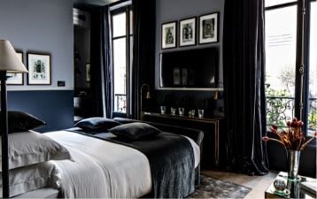 Luxurious Franklin Suite at Monsieur George Hotel & Spa, featuring elegant decor, plush king bed, rich wood furnishings, and soft ambient lighting in Paris