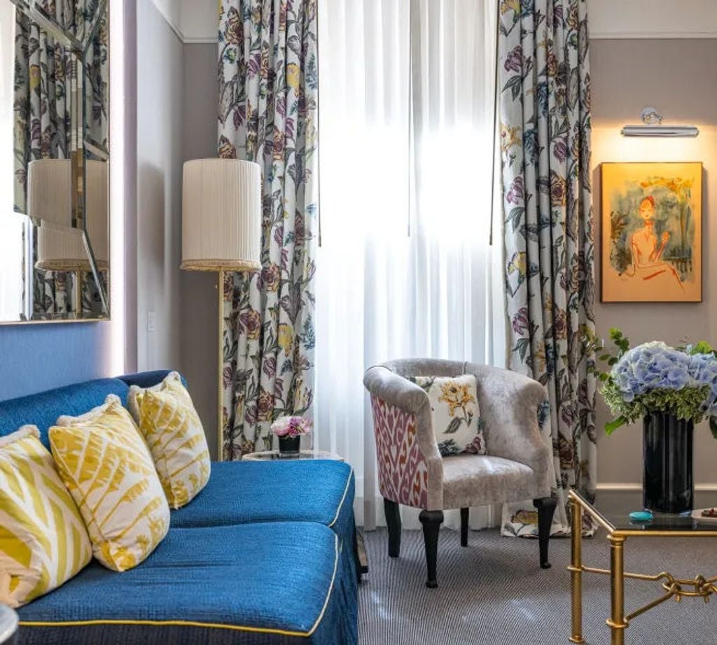 Elegant one-bedroom suite with emerald-toned walls, crystal chandelier, gilded mirrors, velvet furnishings, and ornate moldings in Rome