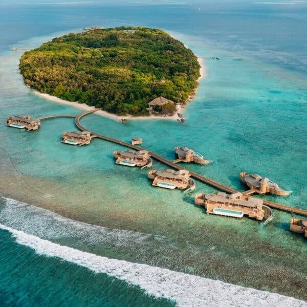 Aerial view of overwater villas in Maldives with wooden walkways connecting luxury suites above crystal-clear turquoise lagoon