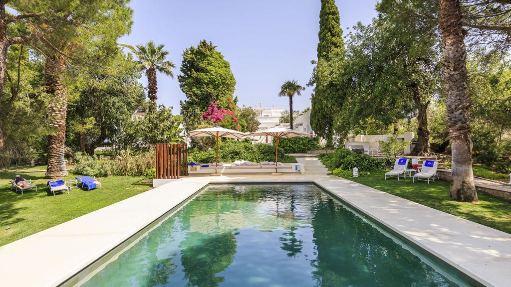 Whitewashed luxury Portuguese villa with terracotta roof nestled among manicured gardens and towering palm trees at sunset