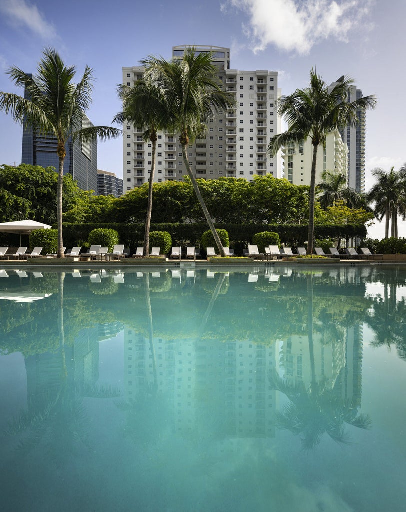 Luxurious beachfront resort with modern glass tower, private balconies, and pristine white sand beach along turquoise ocean waters